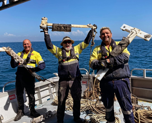 Three men from the Noise theme team hold up recorders they retrieved from Cockburn Sound.