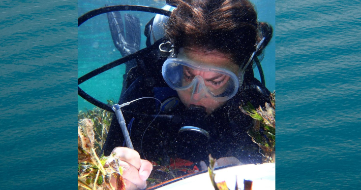 Alicia Sutton at work underwater with notepad (with background image)